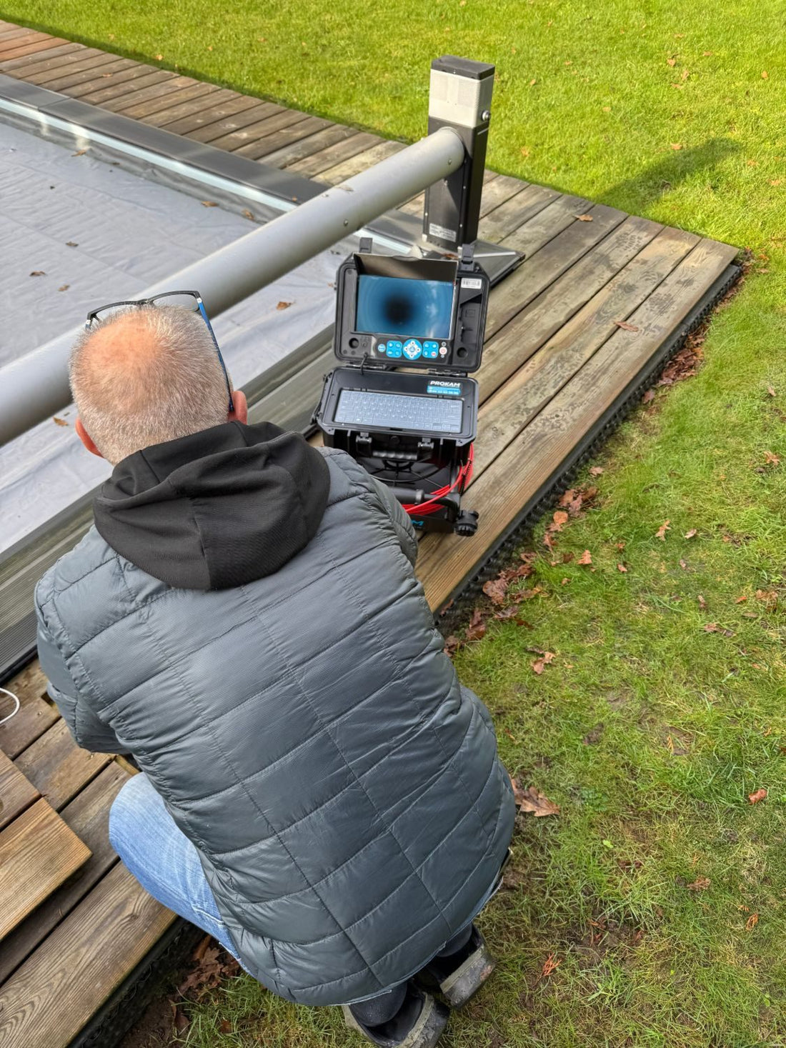 Technicien devant l'écran d'une caméra d'inspection PROKAM au bord d'une piscine